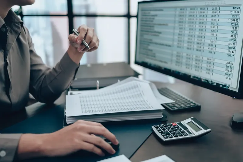 Boekhouder verwerkt de financiële administratie met spreadsheets en een rekenmachine