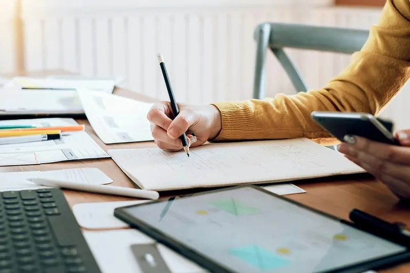Ondernemer controleert facturen en bonnen aan een bureau met laptop en tablet