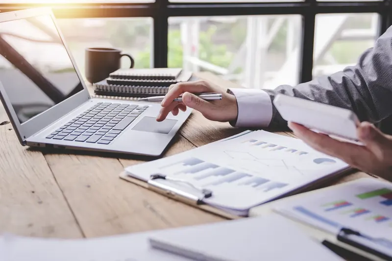 Laptop en papieren rapportages met grafieken op een bureau
